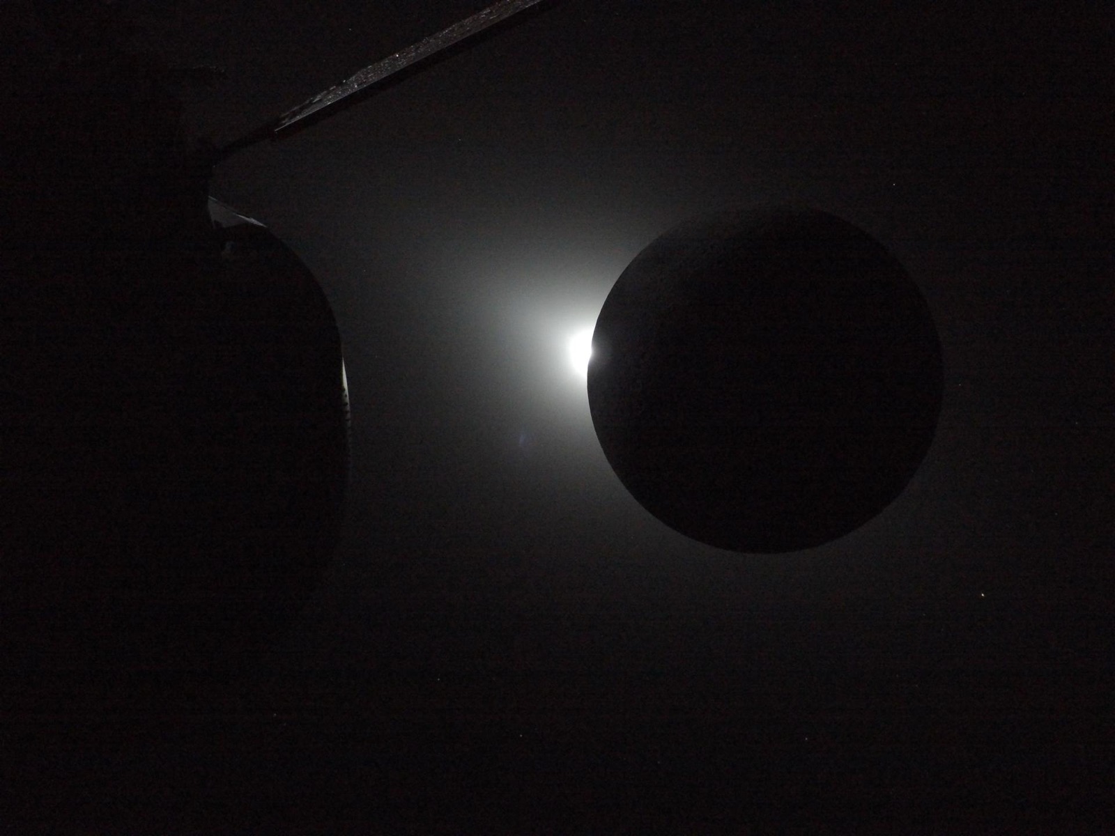 El Sol asoma por el borde de la Luna, con Orion en primer plano